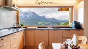 Una cocina con armarios de madera, un lavamanos y una ventana con vistas a un paisaje montañoso.
