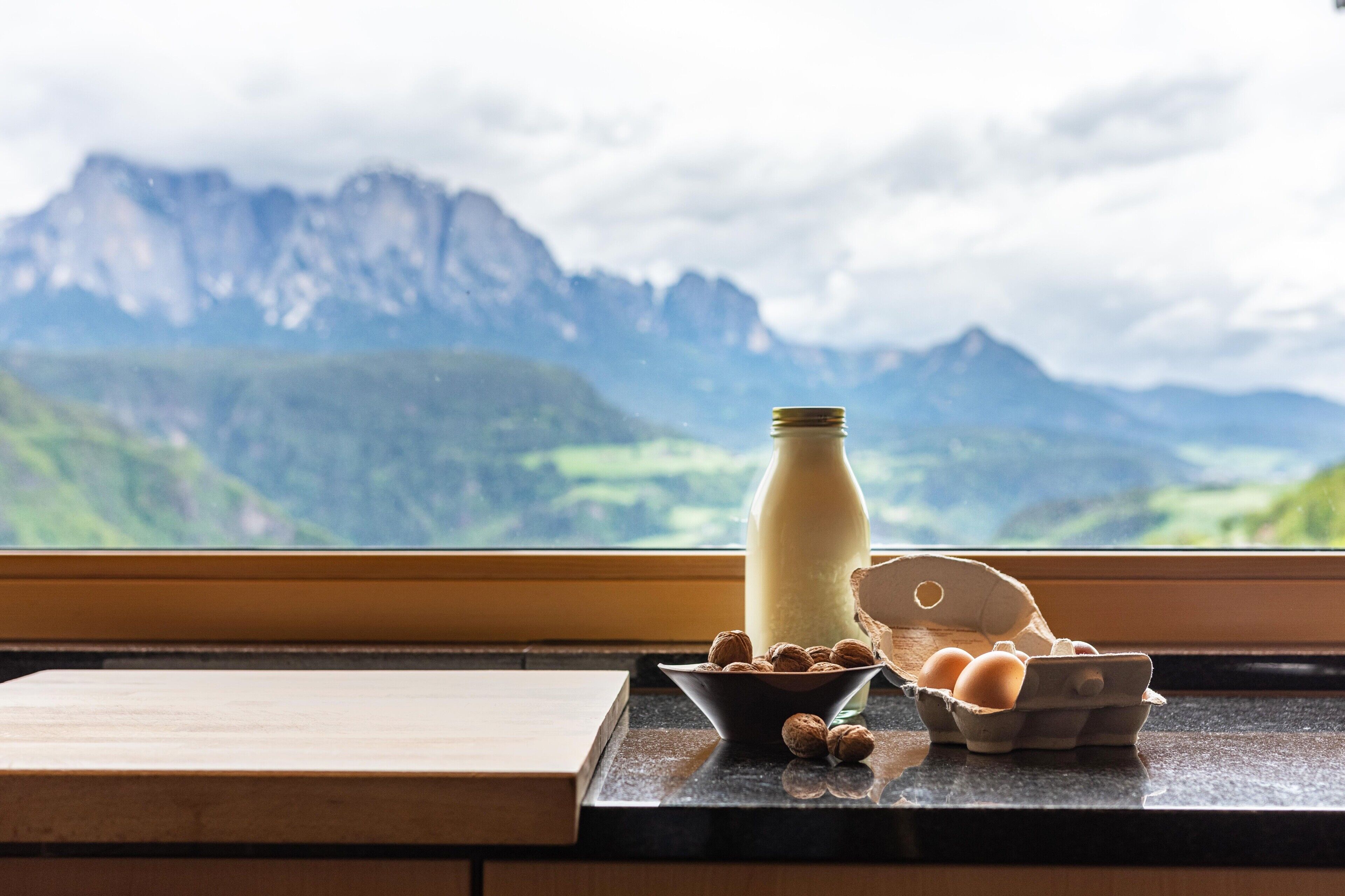 A kitchen counter with a bottle, a bowl of walnuts, and an egg carton.