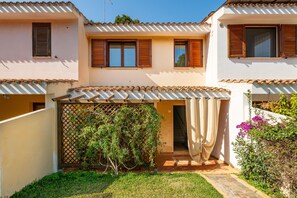 Un bâtiment à deux étages doté d’un patio couvert, d’une clôture en bois et d’un petit jardin.