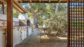 An outdoor kitchen area with a brick oven, a pergola, and a stone pathway. - Holiday Home 'Sole E Mare' with Private Terrace, Private Garden and Air Conditioning (Porto Pino)