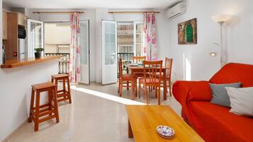 A living room with a red sofa, wooden coffee table, and a dining area with chairs and a table.