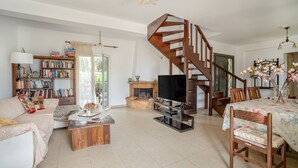 Ein geräumiges Wohnzimmer mit einer Holztreppe, einem Kamin, einem Fernseher und einem Bücherregal.