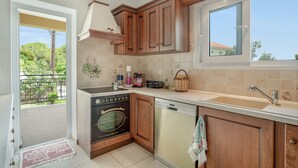 Eine Küche mit Holzausstattung, einem Backofen, einem Geschirrspüler und einem Fenster mit Blick ins Freie.