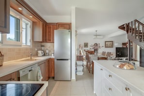Una cocina moderna con armarios de madera, un refrigerador de acero inoxidable y una zona de comedor con mesa y sillas.