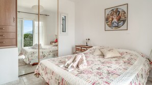 Ein Schlafzimmer mit einem großen Bett, einem Spiegel, einem Gemälde und Blick ins Freie.