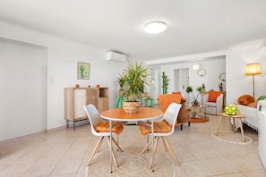 A dining area with a round table, two chairs, a potted plant, and a lamp.