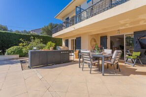 Une terrasse avec un barbecue, des sièges d’extérieur et une vue sur un immeuble.
