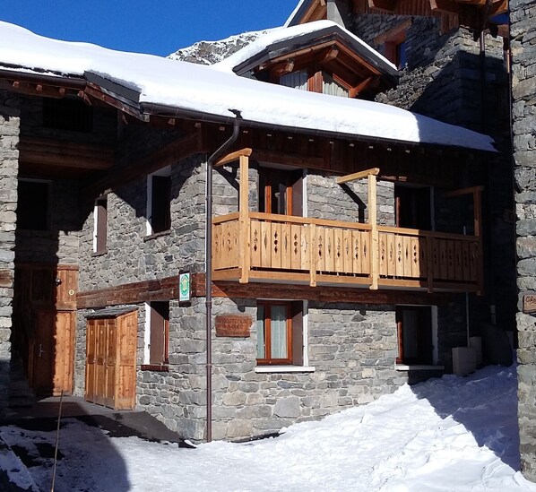 Un bâtiment en pierre doté d’un balcon en bois et d’une enseigne indiquant qu’il s’agit d’une maison d’hôtes.