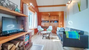 A cozy living room with a TV, a sofa, two chairs, and a fireplace.