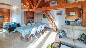 A spacious living area with a dining table, a sofa, and a staircase leading to an upper level.