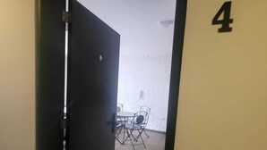 A doorway leading to a room with a table and chairs, a number '4' on the wall, and a white textured wall. - 4. Calido Apartaestudio, Casa Azul Manizales Caldas, Colombia (Manizales)