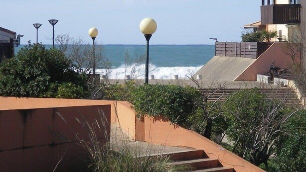 A coastal view with a building featuring a balcony and a staircase leading to a deck overlooking the sea. - CAPBRETON Residence "Les Terrasses de Notre-Dame", west facing with ocean views (CAPBRETON)
