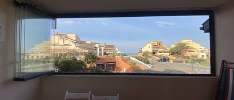 A room with a large window offering a view of a residential area with houses and a road.