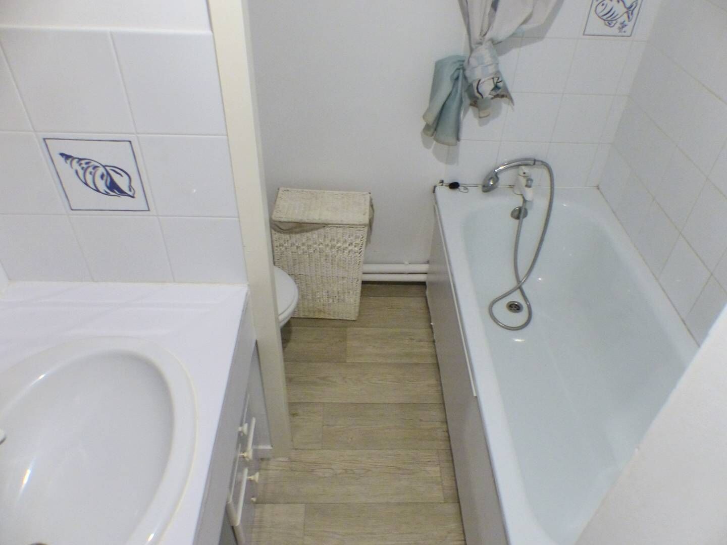 Une salle de bain avec une baignoire, des toilettes et un panier en osier.