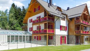 A multi-story chalet with balconies, a stone facade, and a glass conservatory.