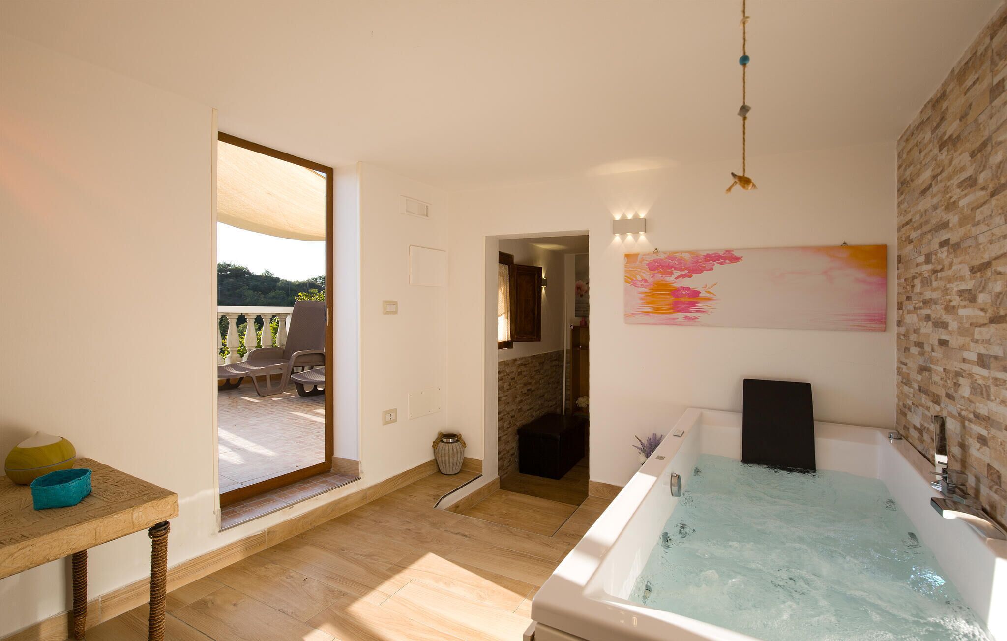 Une salle de bain moderne avec une baignoire, une douche et une vue sur un balcon aménagé avec du mobilier d’extérieur.