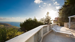 Une terrasse avec vue sur la mer, des balustrades en pierre et un bâtiment doté d’un balcon.