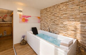 A modern bathroom with a large bathtub, wooden wall paneling, a decorative painting, and a small plant. - Amazing apartment in Cetraro with sauna (Cetraro)