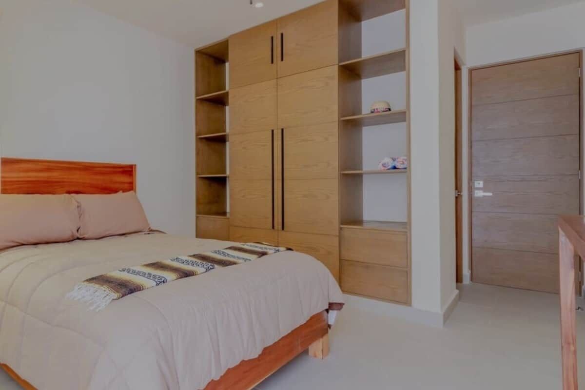 A bedroom with a bed, wooden wardrobe, and a door.