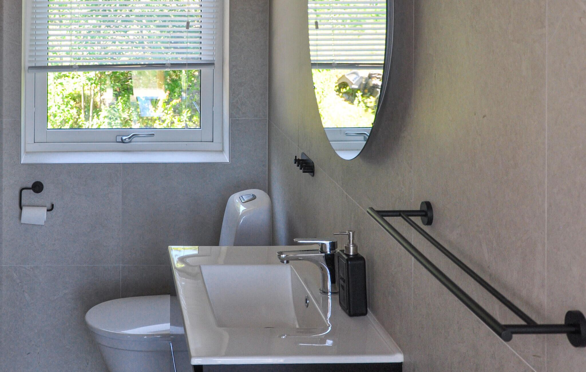 Ein modernes Badezimmer mit Toilette, Waschbecken und Spiegel.