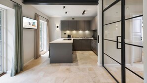 Una cocina moderna con una isla central, armarios oscuros y una puerta corrediza de vidrio que da a un comedor.