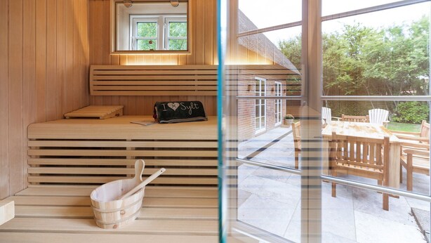 Una sauna con bancos de madera, un banco con toalla y ventana con vista a un jardín.