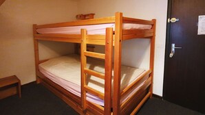 A bunk bed in a room with a door and a small table.