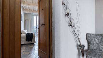 Una stanza con una porta in legno, un divano, una poltrona a motivi decorativi e un elemento decorativo a parete.
