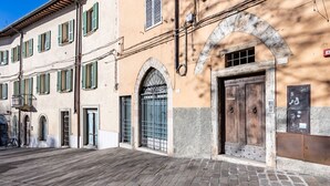 A street with a building featuring a large wooden door, arched windows, and a balcony with a metal railing. - GuestHost - Bright apartment perfect for 4 people, with 2 bedrooms and 2 bathrooms, located in a period building in the heart of the historic center (ZTL). The apartment boasts all the main comforts, including a private garden, an oasis of peace and gree (Perugia)