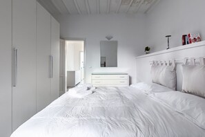 A bedroom with a bed, a dresser, a mirror, and a wardrobe.