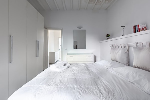 Un dormitorio con una cama, un tocador, un espejo y un armario.