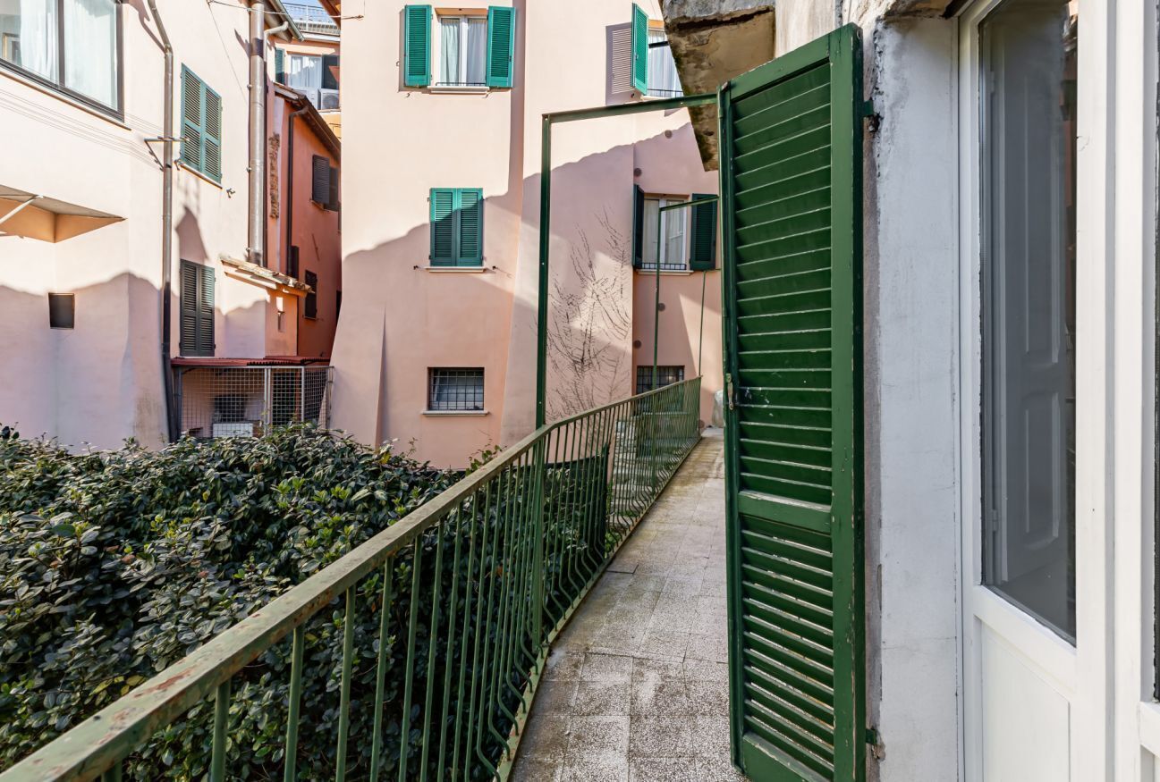 Un vicolo stretto con una ringhiera di metallo, una porta verde e edifici con balconi e finestre.