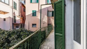 A narrow alleyway with a metal railing, a green door, and buildings with balconies and windows. - GuestHost - Bright apartment perfect for 4 people, with 2 bedrooms and 2 bathrooms, located in a period building in the heart of the historic center (ZTL). The apartment boasts all the main comforts, including a private garden, an oasis of peace and gree (Perugia)