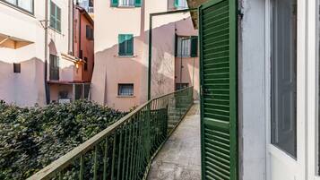 Un vicolo stretto con una ringhiera di metallo, una porta verde e edifici con balconi e finestre.
