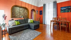 A living room with a sectional sofa, a dining table, and chairs.