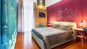 A bedroom with a bed, a wall with circular decorations, a hanging light fixture, and a nightstand with a lamp.