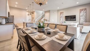 Une cuisine moderne avec un coin repas, un escalier et un salon doté d’un canapé et d’une télévision.
