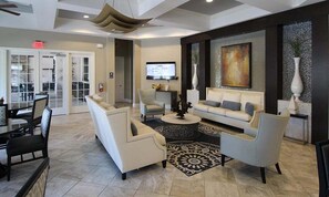 A modern living room with a sofa, armchairs, a coffee table, and a TV.