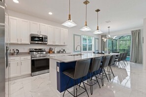 A modern kitchen with white cabinets, stainless steel appliances, and a central island with bar stools.