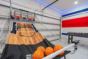 Un terrain de basket avec des paniers, un plancher en bois et une table où sont rangés les ballons.