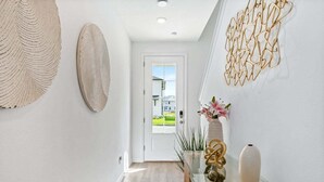 A hallway with a glass table, decorative wall art, and a view of a house through a door. - Lovely Townhome| Sleeps 8 (Davenport)
