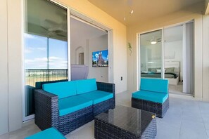A balcony with a sofa, a coffee table, and a TV screen.