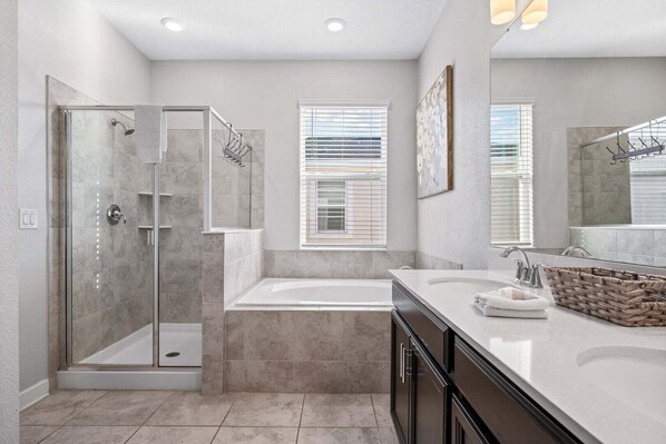 Une salle de bain moderne dotée d’une douche à parois de verre, d’une baignoire sur pieds et d’un meuble-lavabo avec un grand miroir.