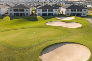 A golf course with bunkers and a clubhouse in the background.
