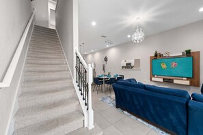 A staircase leading to a dining area with a blue sofa and a TV in the living room.