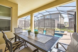 A patio with a table and chairs, a pool, and a greenhouse structure.