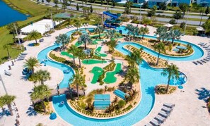 Vista aérea de un resort con una gran piscina, varias toboganes acuáticos y un campo de golf.