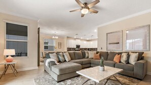 A modern living room with a sectional sofa, a coffee table, and a ceiling fan.