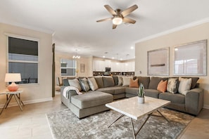 A modern living room with a sectional sofa, a coffee table, and a ceiling fan.