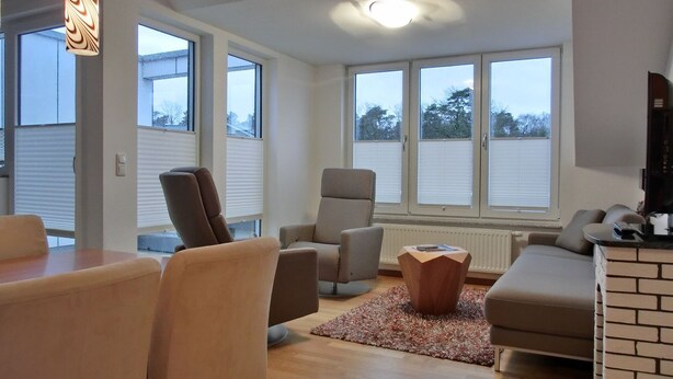 Una sala de estar moderna con comedor, ventanas amplias y chimenea.